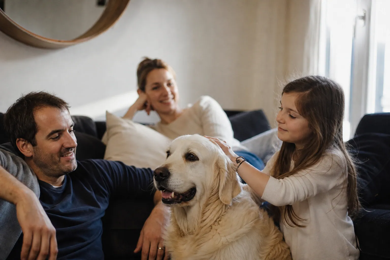 Une famille française avec un enfant qui caresse un chien dans le salon