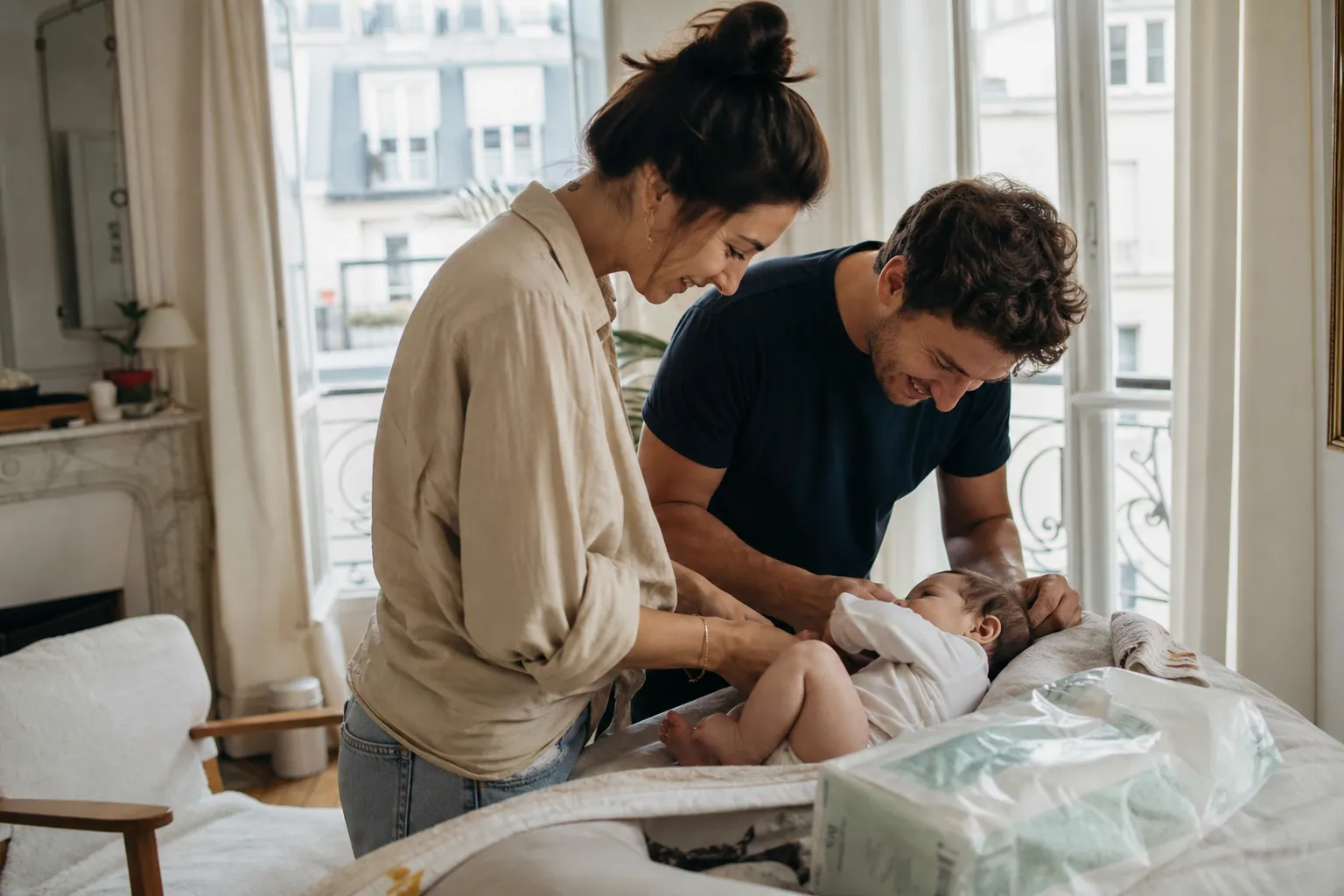 Parents français changeant leur bébé à la maison avec une couche jetable