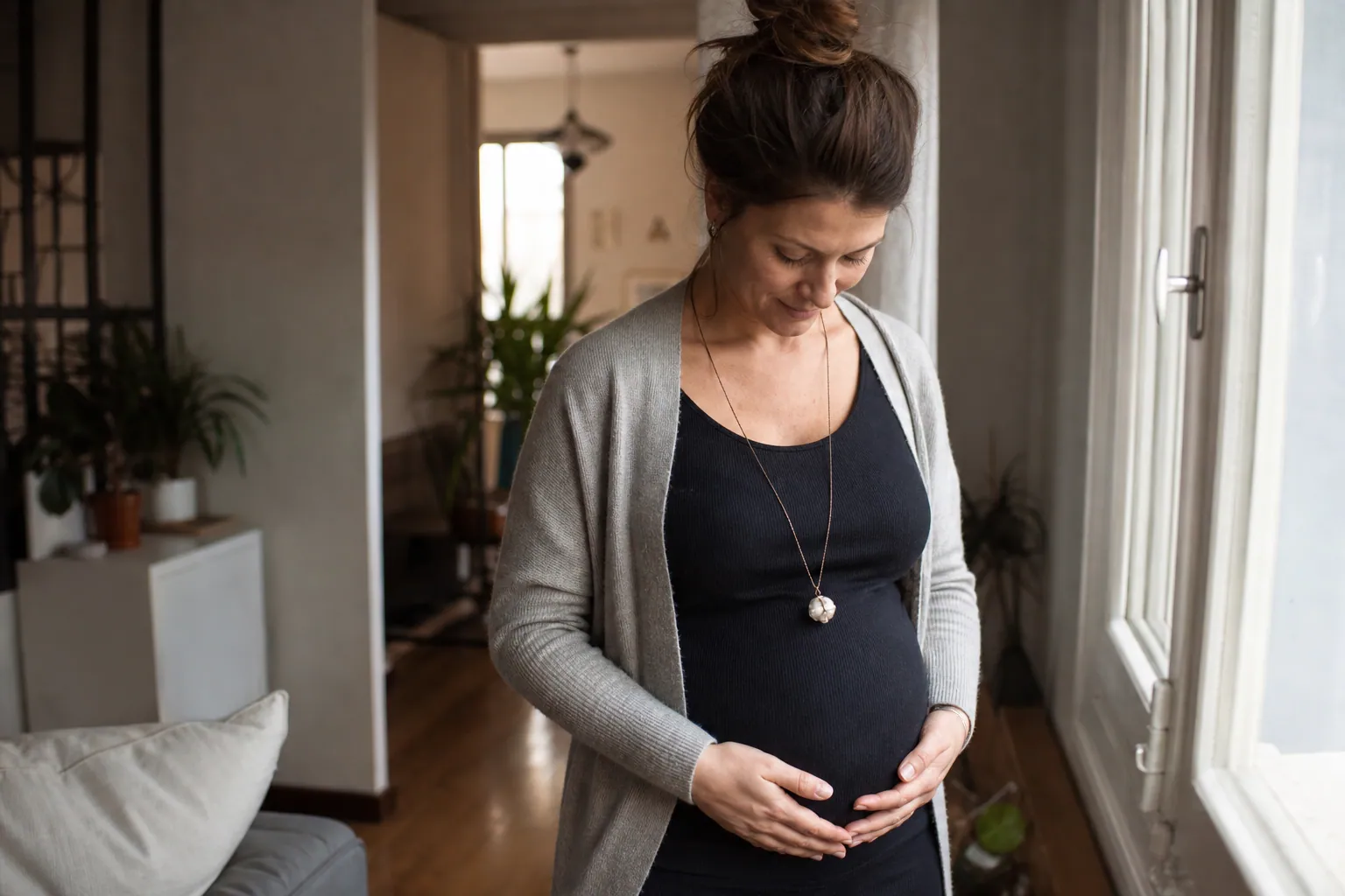 Future maman portant un bola de grossesse près du ventre, dans une ambiance douce et naturelle.