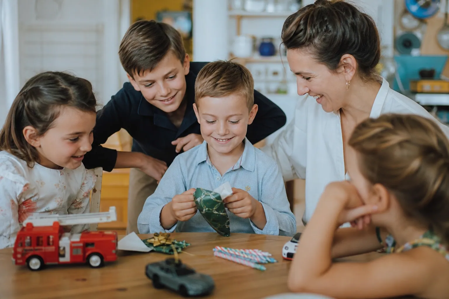 Enfant ouvrant un cadeau d’anniversaire avec sa famille autour de lui.
