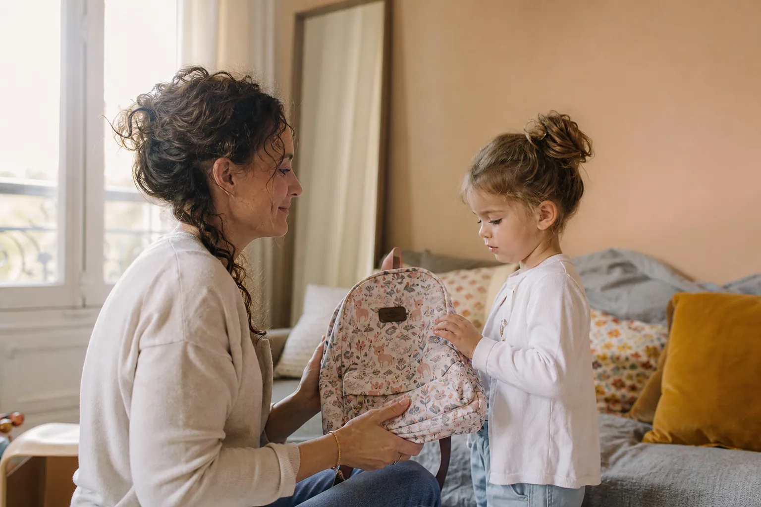 Parent et enfant choisissant un cartable de maternelle à la maison