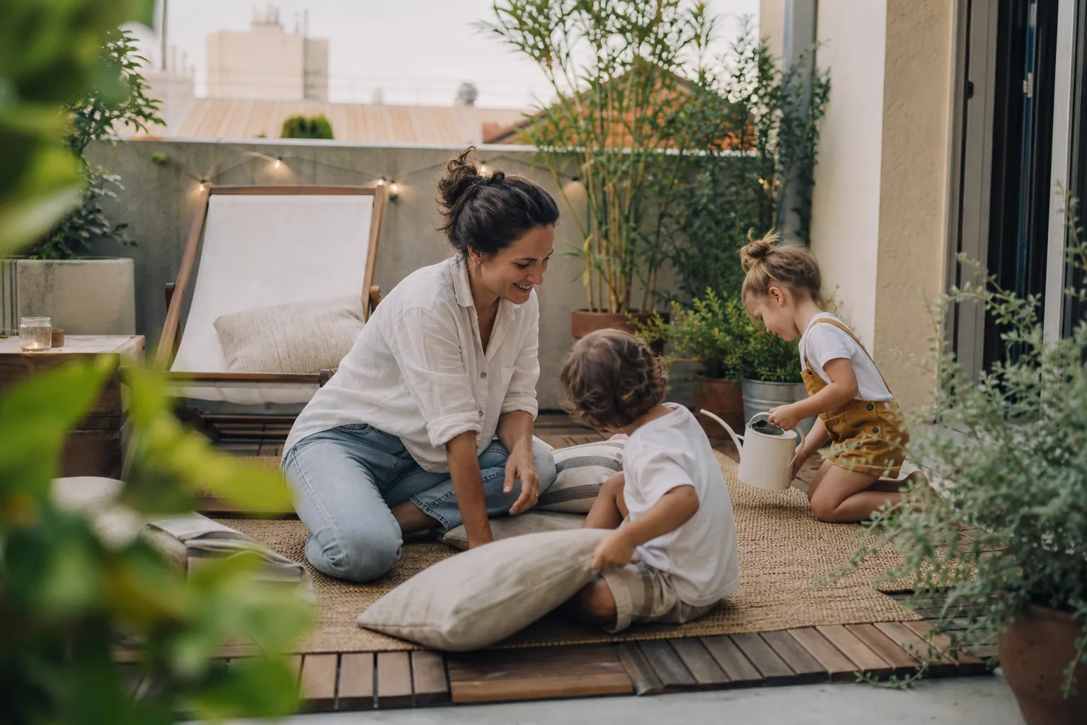 Terrasse en béton décorée avec bois, plantes, tapis et lumière douce