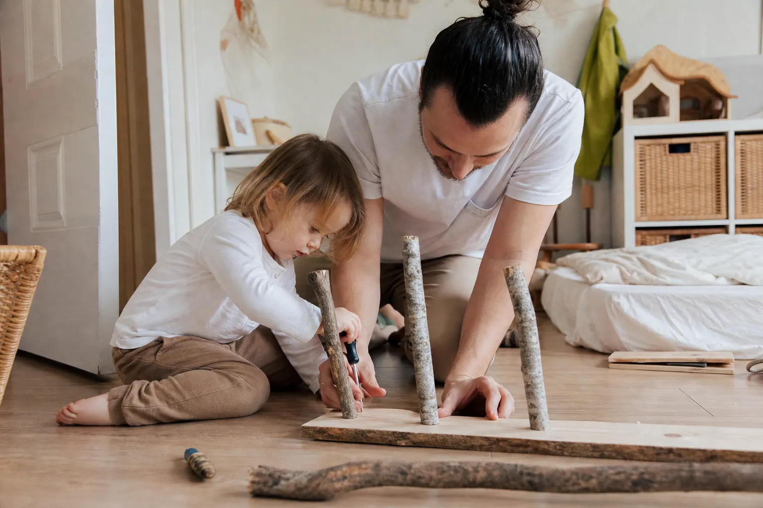 Parent et enfant fabriquant une étagère murale rustique avec des branches et une planche