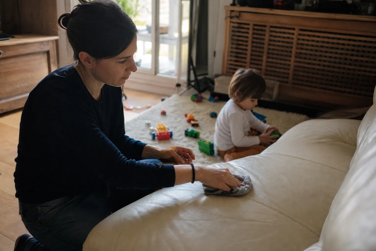 Parent nettoyant une tache sur un canapé en cuir avec un chiffon doux
