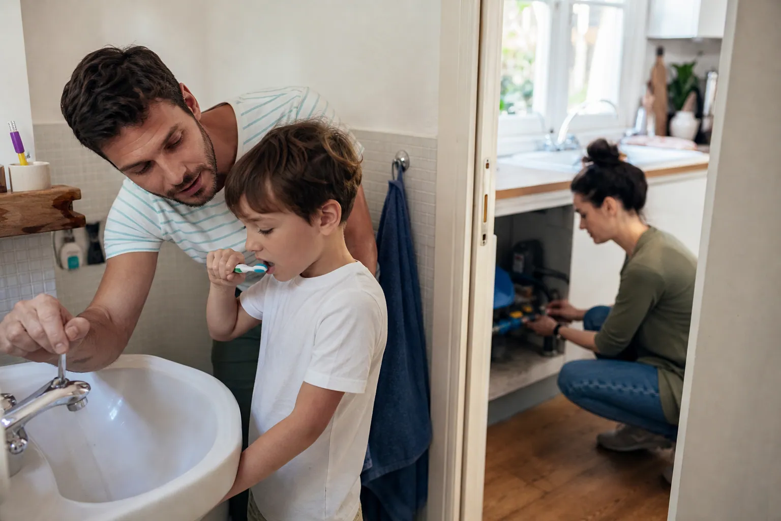 Parent et enfant apprenant à économiser l’eau dans une salle de bains familiale.