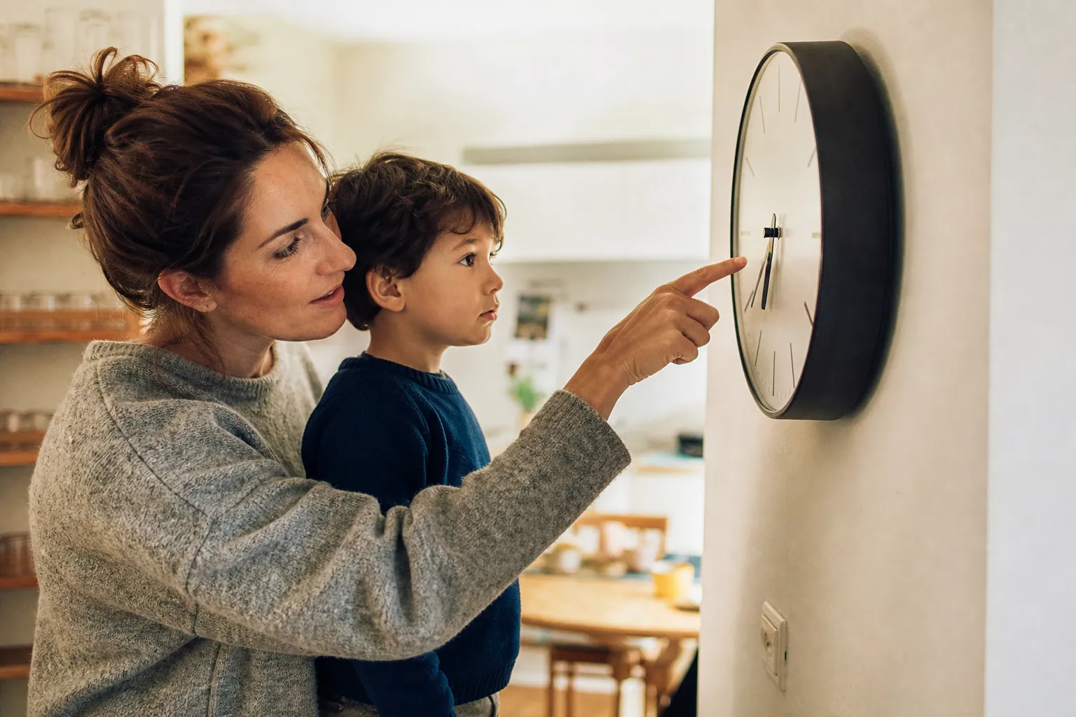 Parent aidant un enfant à lire l’heure sur une horloge murale