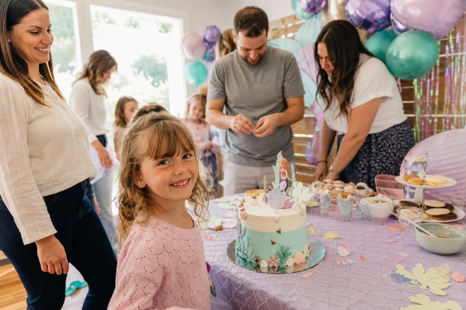 Famille préparant un anniversaire à thème autour d’une table décorée