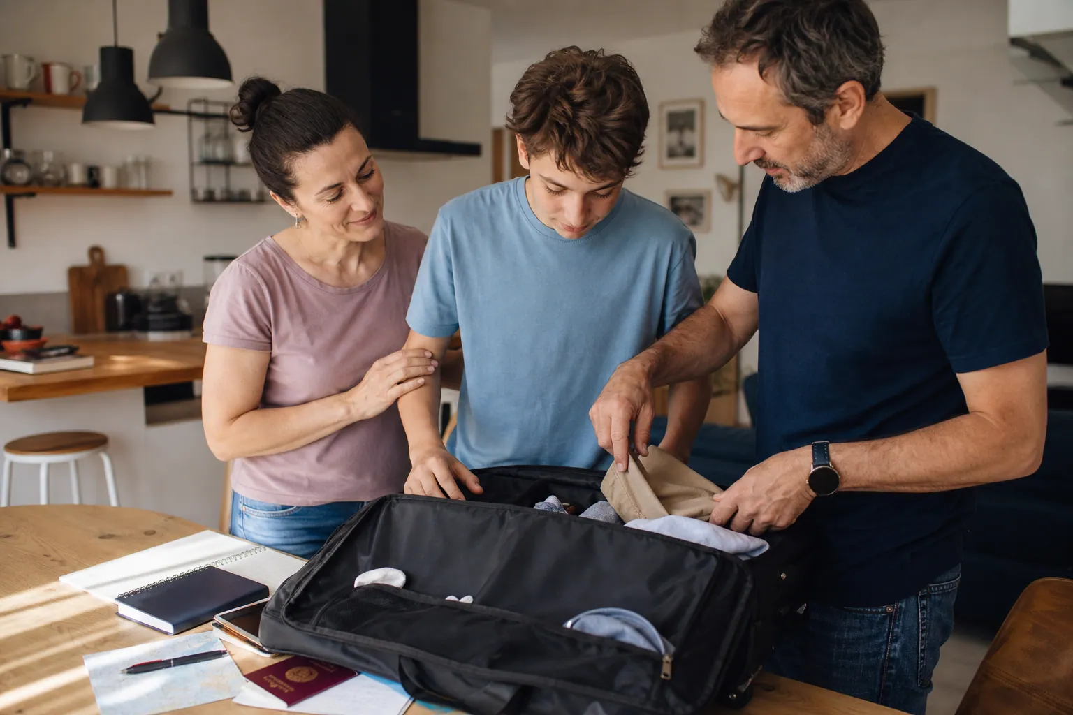 Parent et ado préparent ensemble une valise et des papiers avant un séjour linguistique.