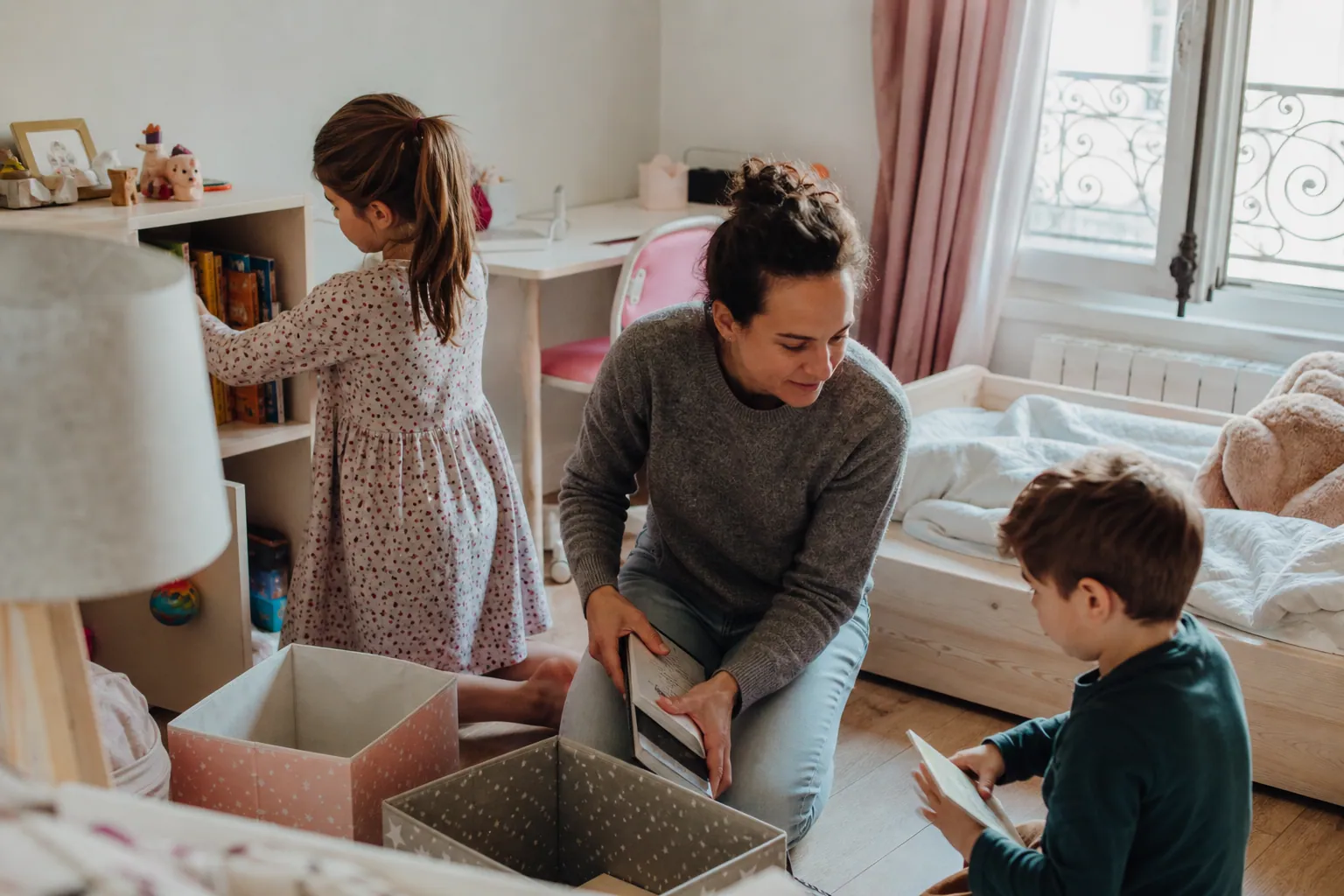 Parent et enfant réaménageant une chambre d’enfant lumineuse avec rangements et peinture claire.