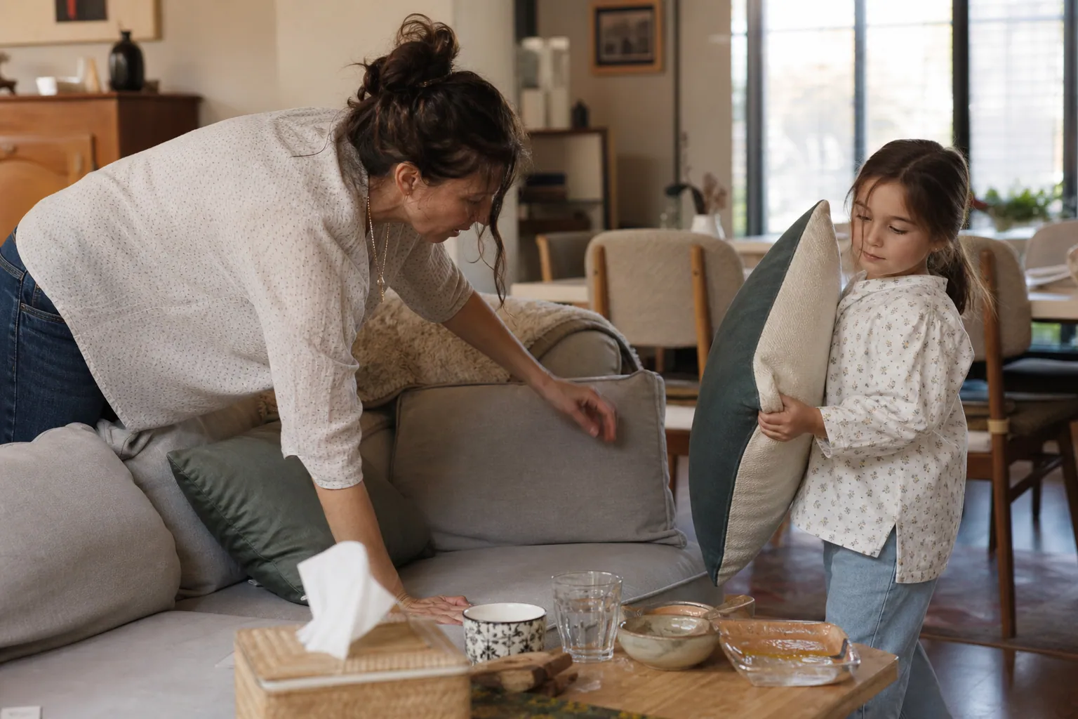 Un parent cherche ses lunettes dans le salon pendant qu’un enfant l’aide.