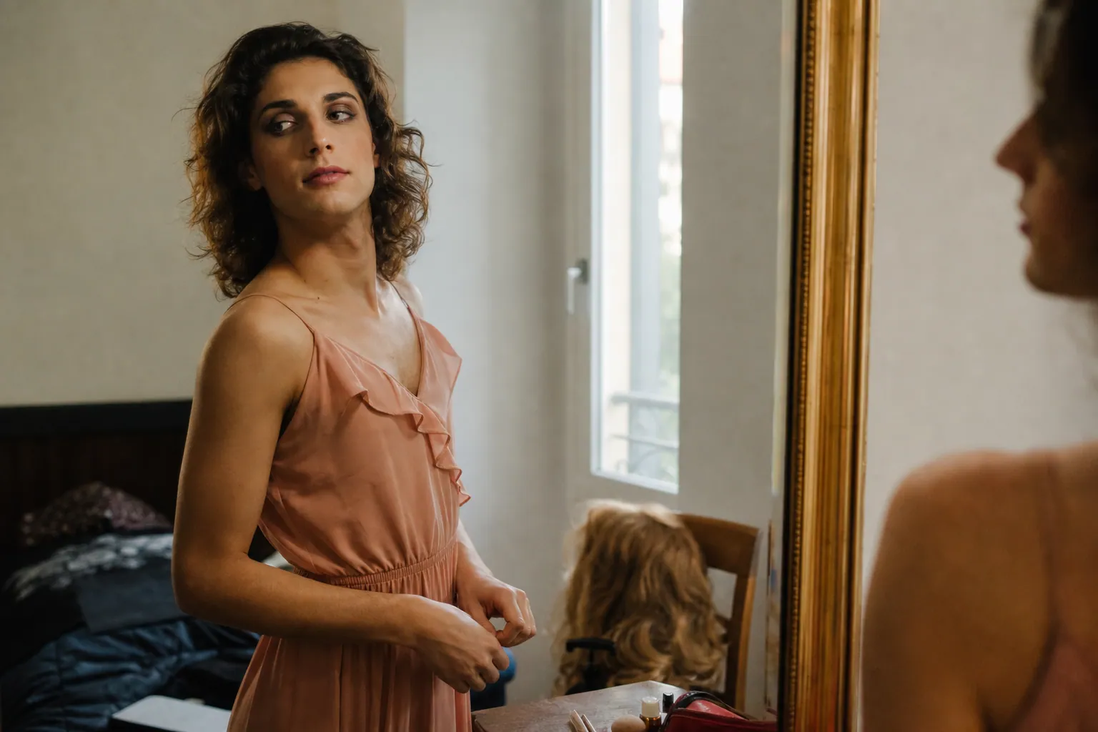 Jeune adulte préparant un déguisement féminin devant un miroir