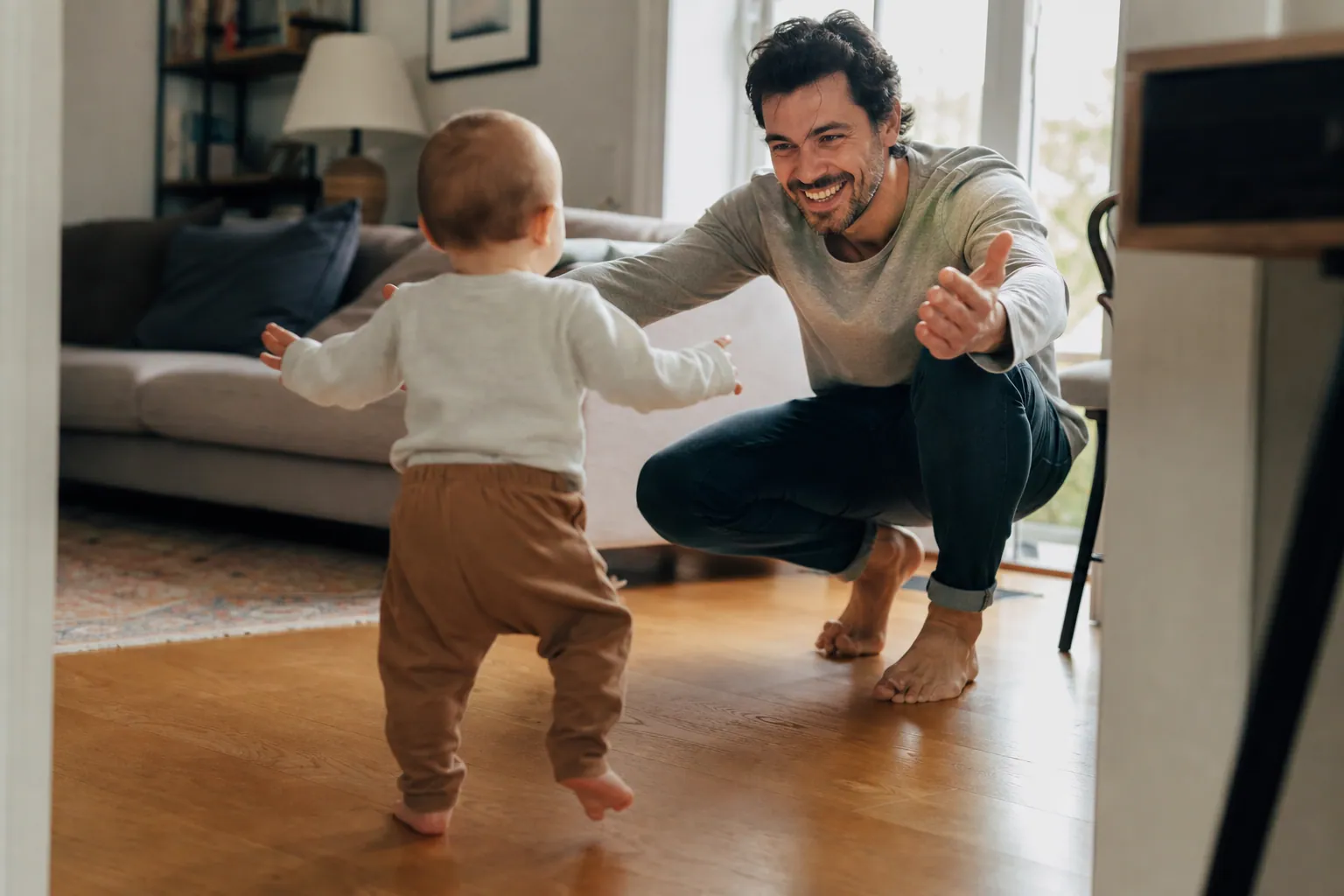 Bébé faisant ses premiers pas vers son parent dans un salon lumineux