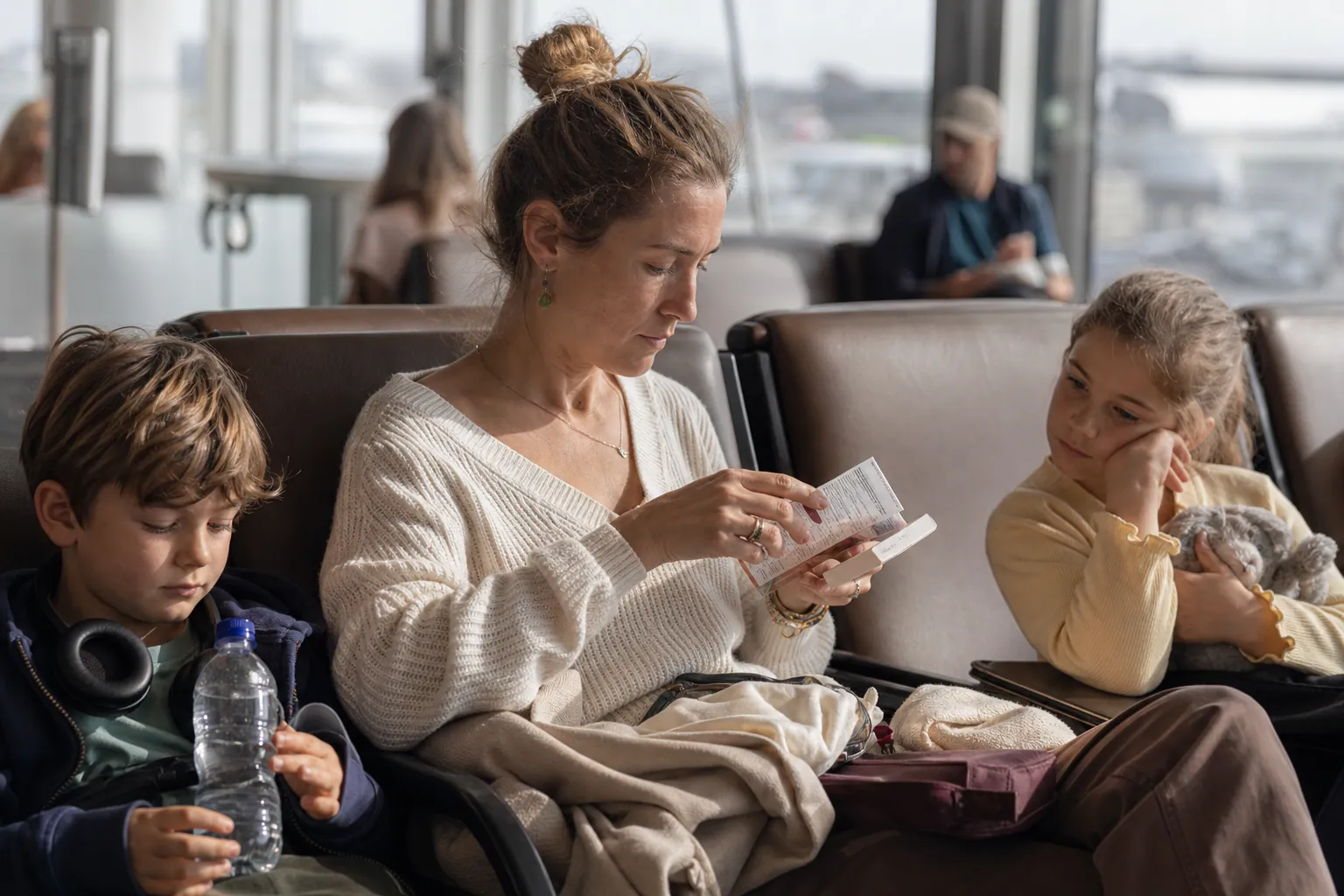 Parent et enfants à l’aéroport avec une boîte de Sedatif PC et une bouteille d’eau.