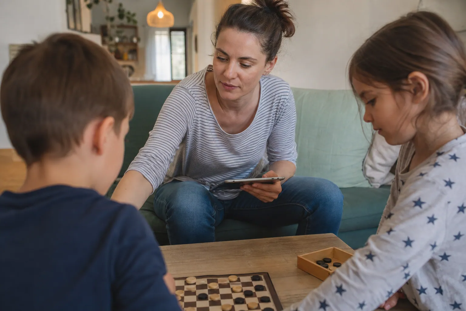 Parent aidant deux enfants à poser la tablette pour jouer en famille