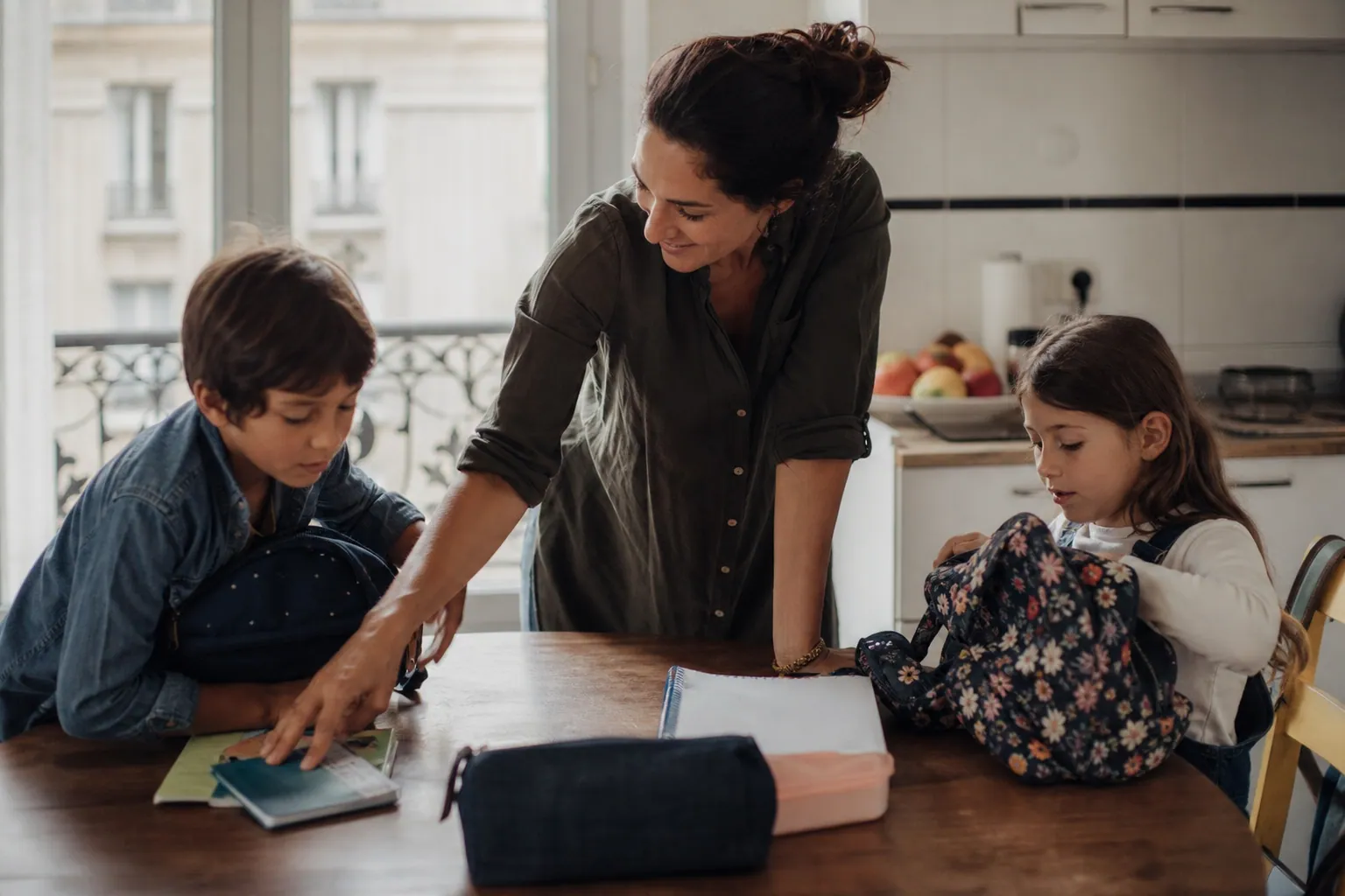 Parent et enfants préparant les cartables à la maison avant la rentrée scolaire