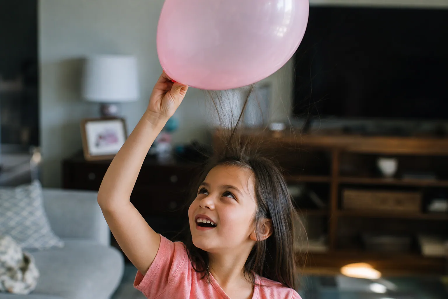 Un enfant tient un ballon près de ses cheveux qui se dressent sous l'effet de l'électricité statique.