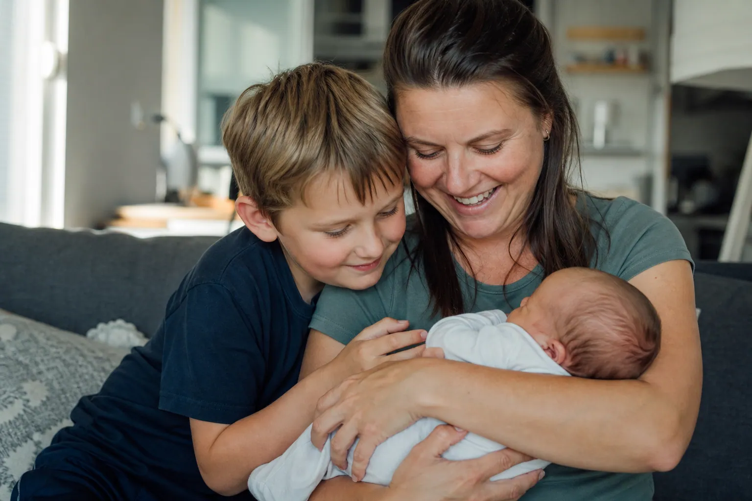 Grand frère aidant doucement un parent à tenir son nouveau-né dans un salon baigné de lumière chaude.
