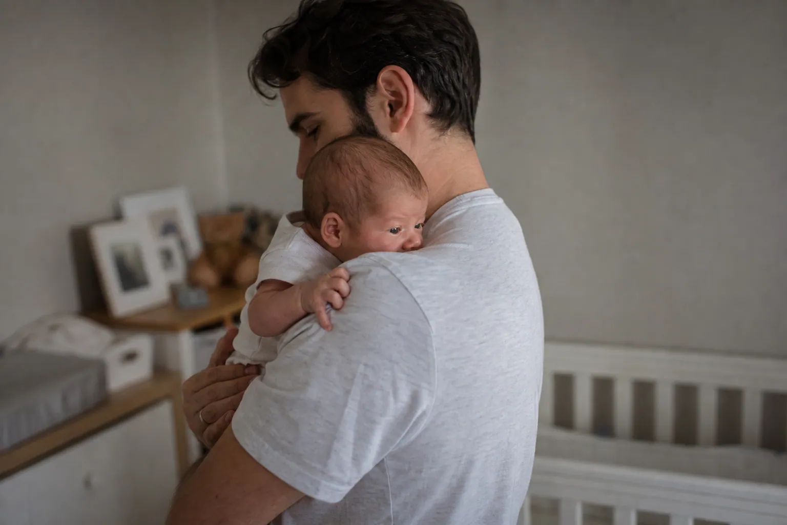 Parent tenant son bébé contre l'épaule après le biberon pour l'aider à faire son rot