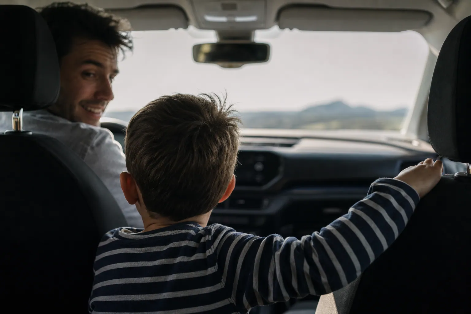 Enfant assis à l'arrière d'une voiture regardant l'horizon à travers le pare-brise en famille.
