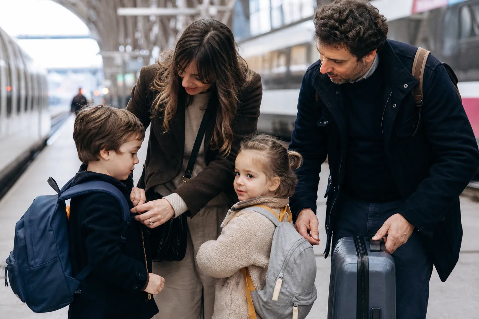 Famille française avec deux enfants en gare, prête à partir en voyage.