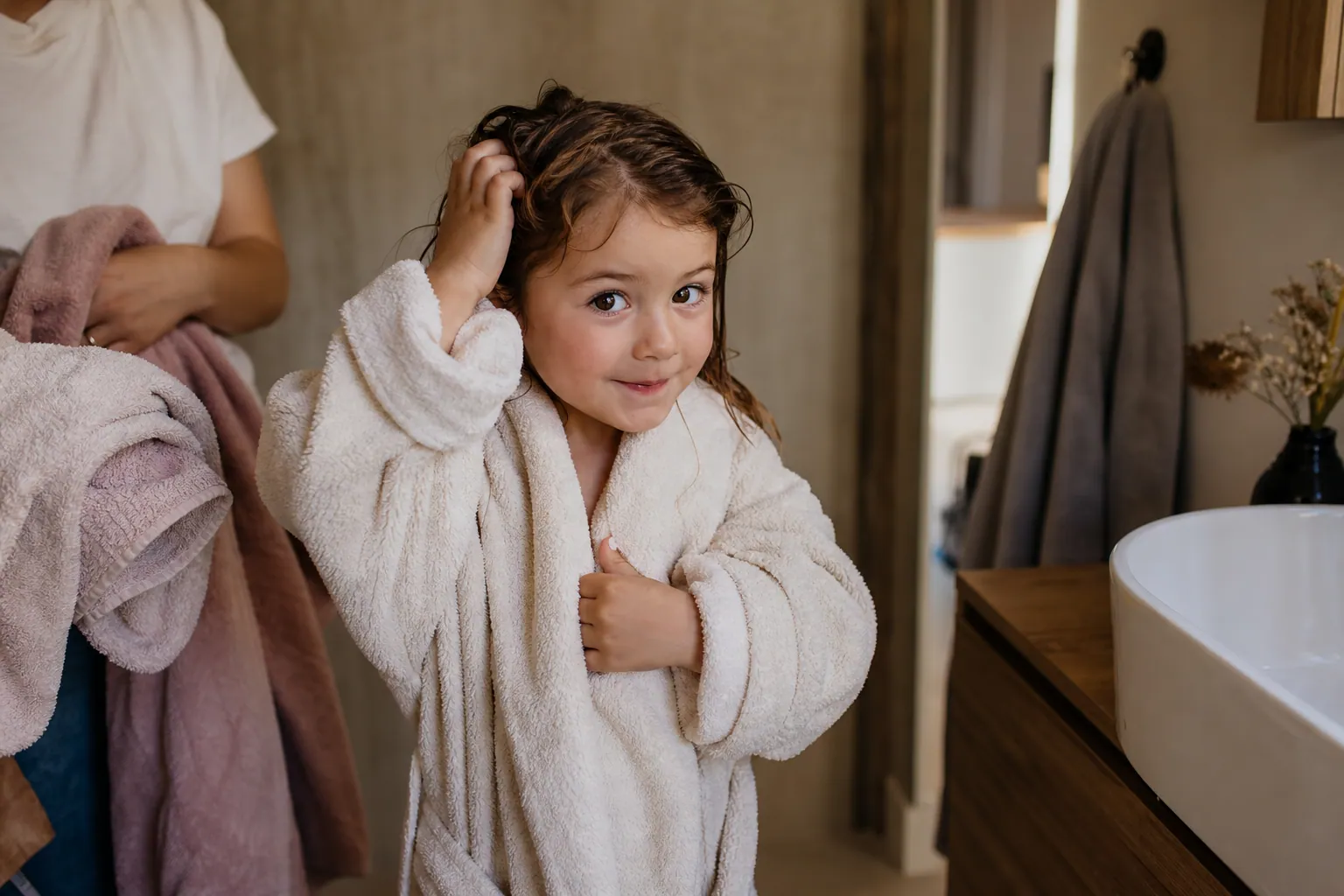 Enfant français enveloppé dans un peignoir doux après le bain, avec un parent à proximité.