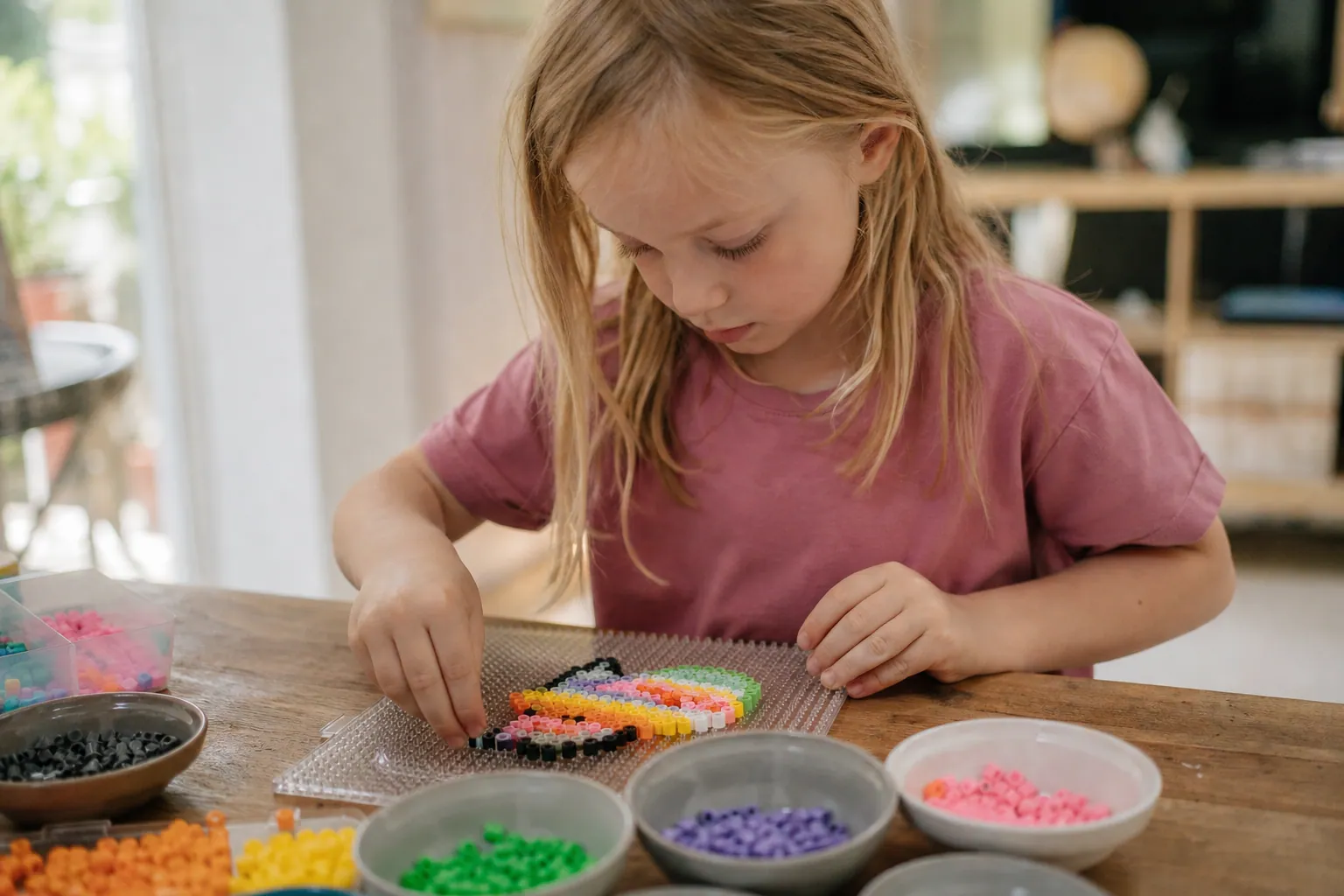 Un enfant place des perles à repasser colorées sur une grille pour créer un motif.