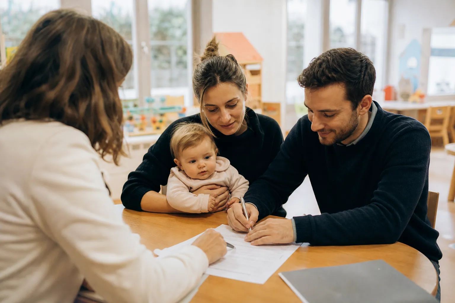 Des parents remplissent un dossier d’inscription en crèche avec leur bébé.