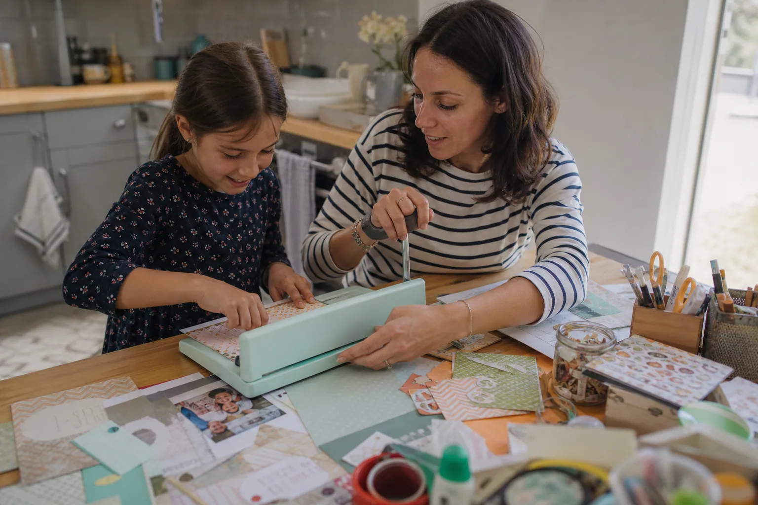 Parent et enfant relient un album de scrapbooking à la maison