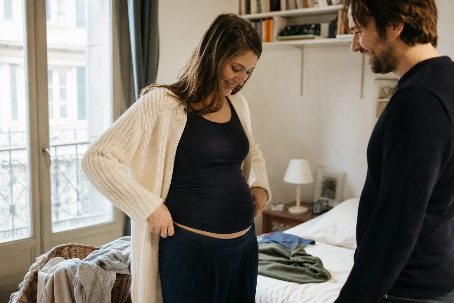 Femme enceinte essayant des vêtements confortables à la maison avec son partenaire