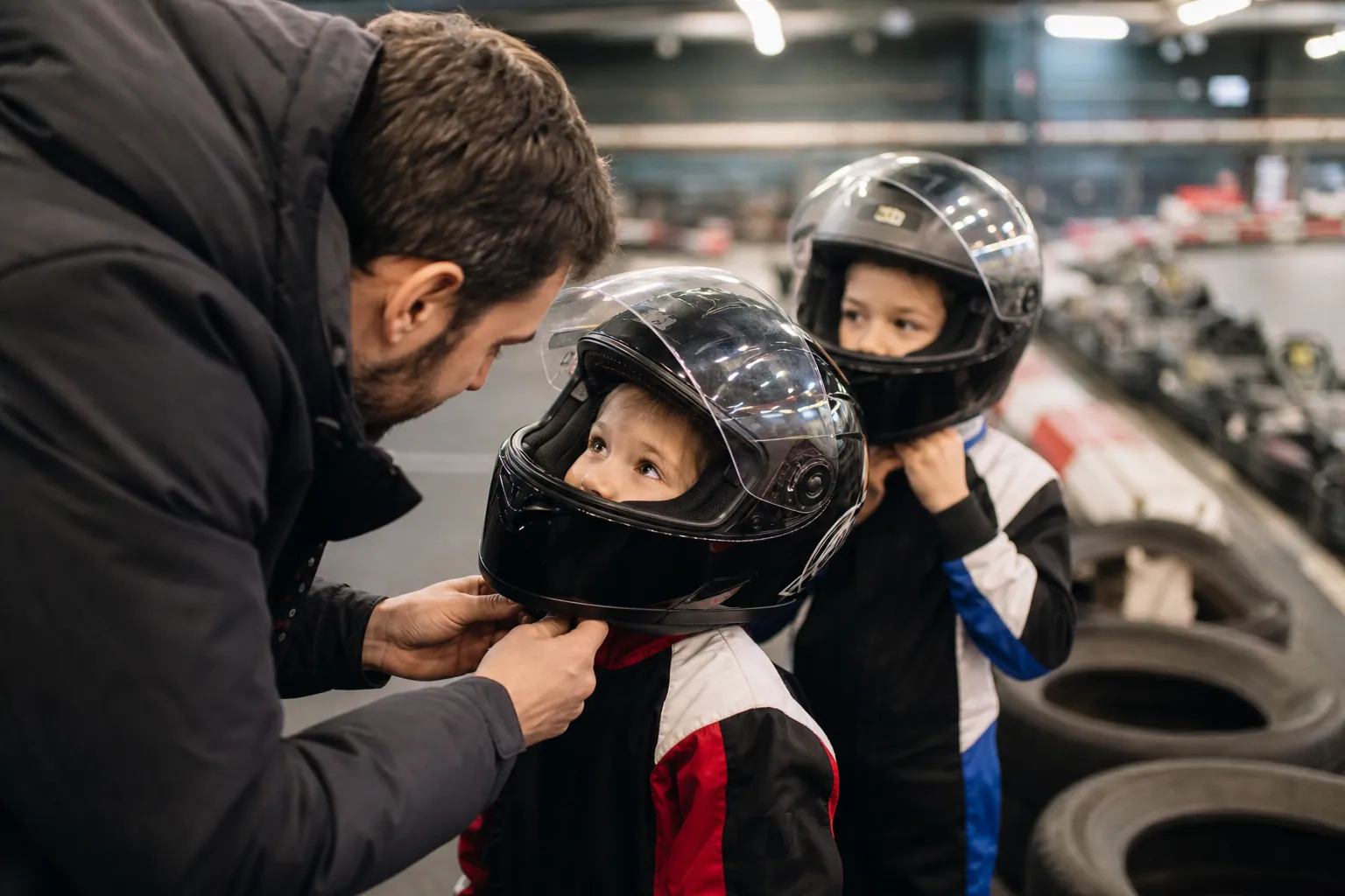 Une famille française prépare une session de karting en intérieur, casques ajustés avant de rouler.