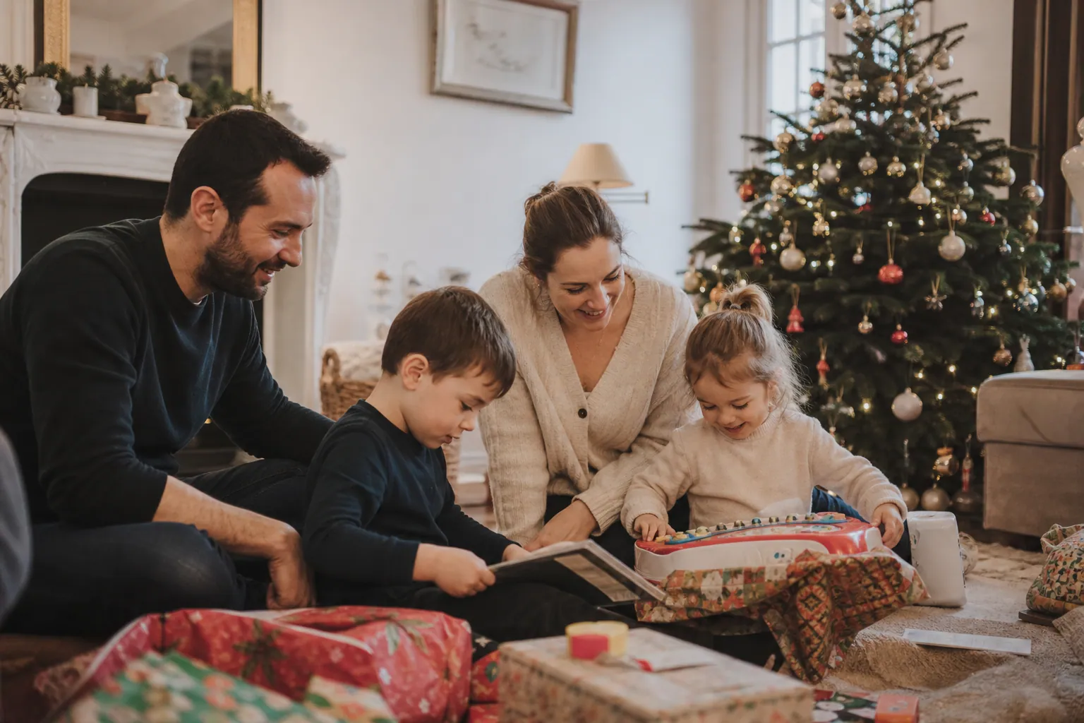 Famille ouvrant des cadeaux de Noël 2012 autour du sapin, avec tablette et jouets