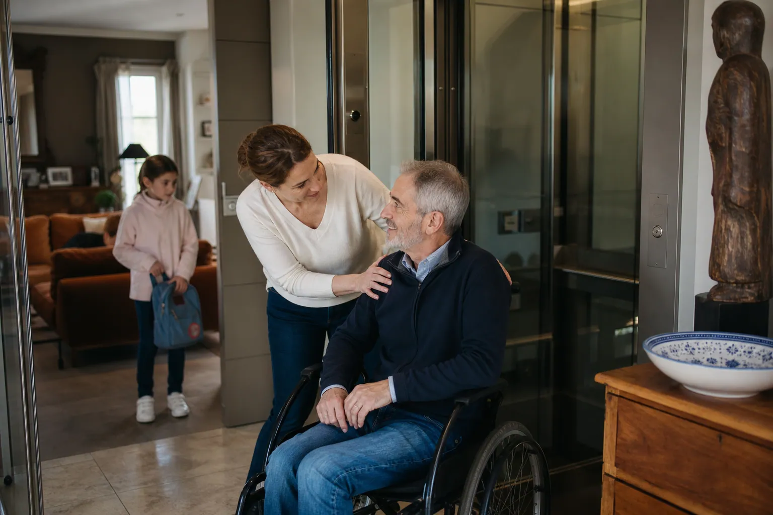 Ascenseur résidentiel dans une maison familiale, avec une personne en fauteuil roulant.