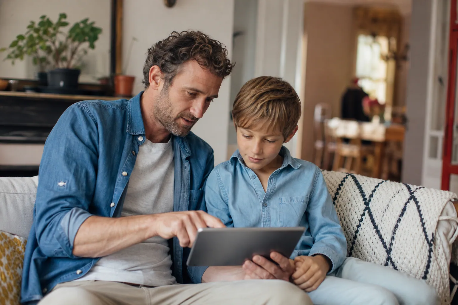Parent accompagnant son enfant devant une tablette dans un salon lumineux, en toute confiance.