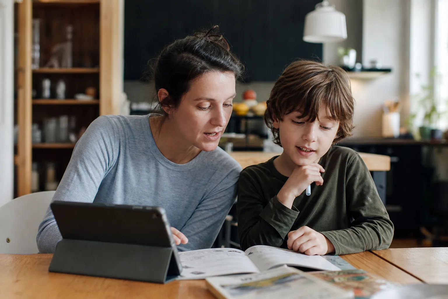 Parent et enfant français discutant d’un nom mystérieux autour d’un livre et d’une tablette.
