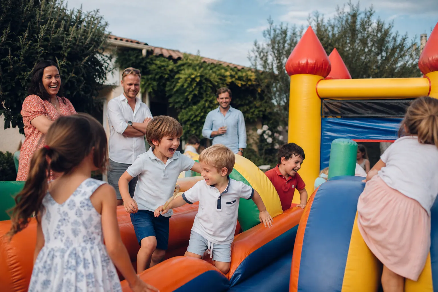 Famille française jouant sur une structure gonflable dans un jardin ensoleillé.