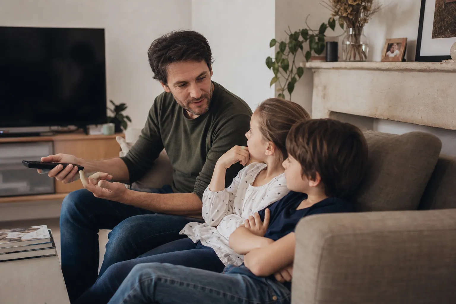 Parent français expliquant une règle télé à deux enfants dans le salon.